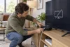 Une personne vérifie les câbles d’un boîtier TV générique après une perte de signal.
